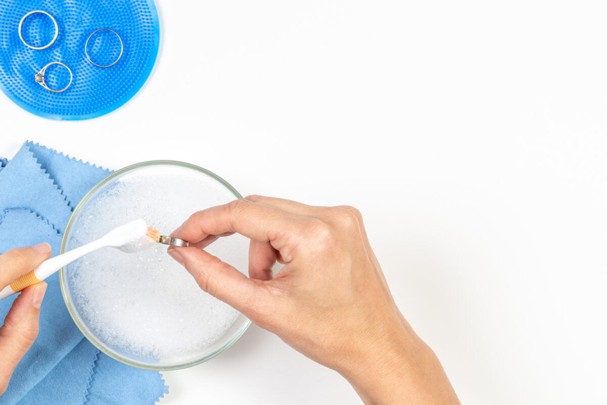 a womans hands cleaning jewellery at home