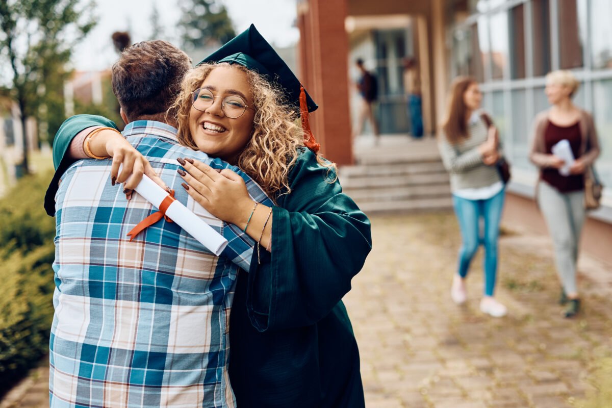 a female graduate hugs her father after receiving her degree certificate