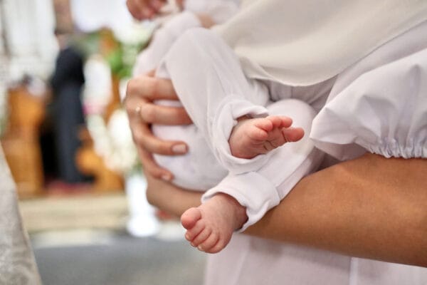 The legs of a newborn during baptism in the church