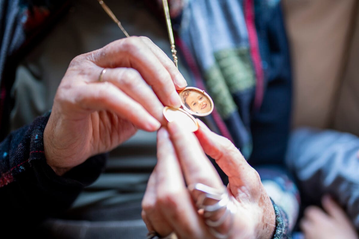 Grandmother opens golden locket revealing grandchild's photo inside
