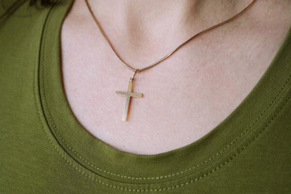 Close up of a woman wearing a simple cross necklace on her chest