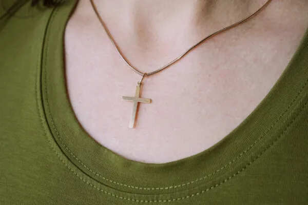 Close up of a woman wearing a simple cross necklace on her chest