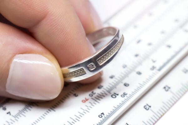 A silver ring in the hands of a master in a pawnshop and a measuring device, macro